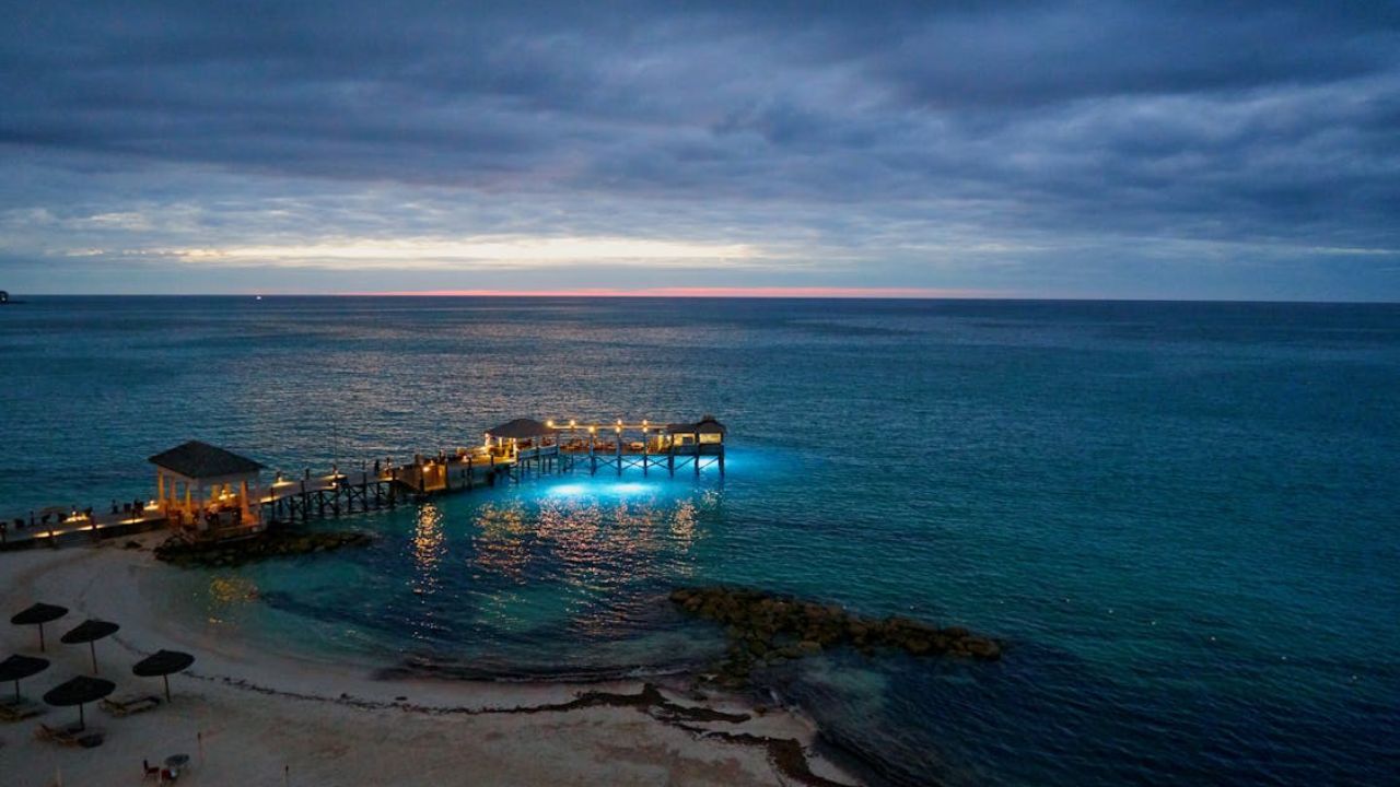 Bahamas pier glowing at twilight over turquoise ocean waters.