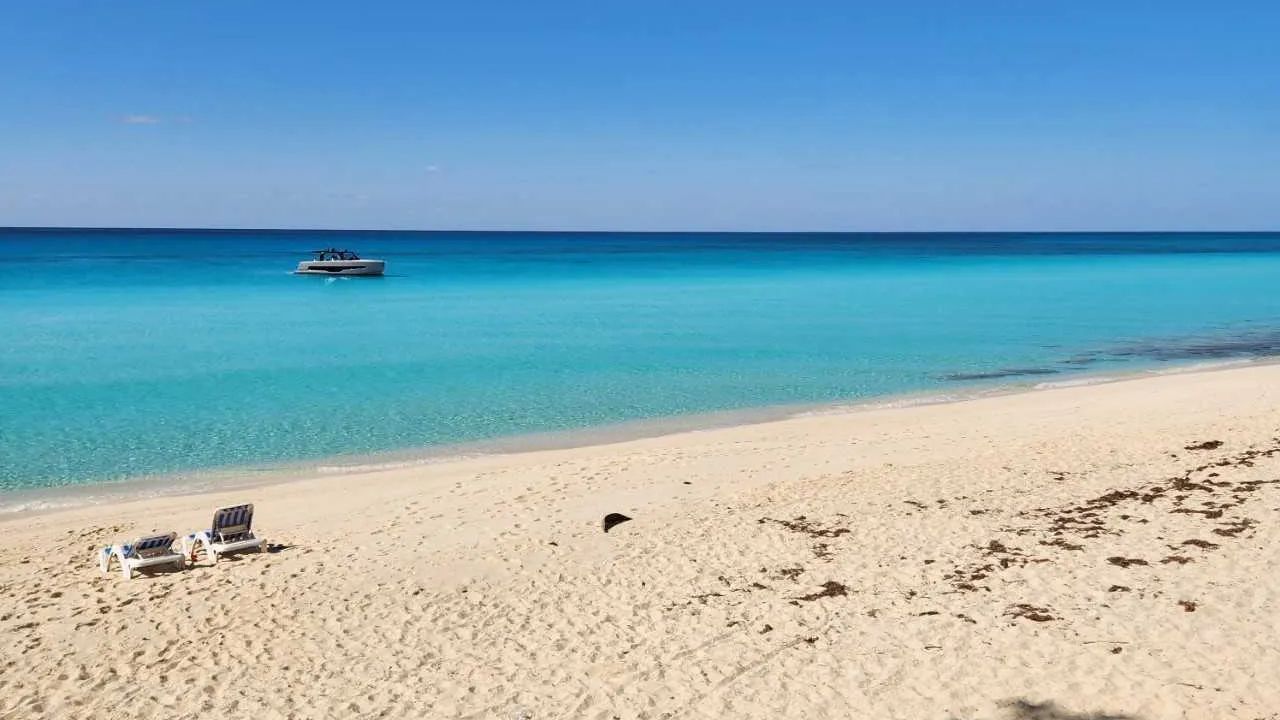 Bimini Beach in Bahamas with turquoise water, lounge chairs, and boat.&nbsp;