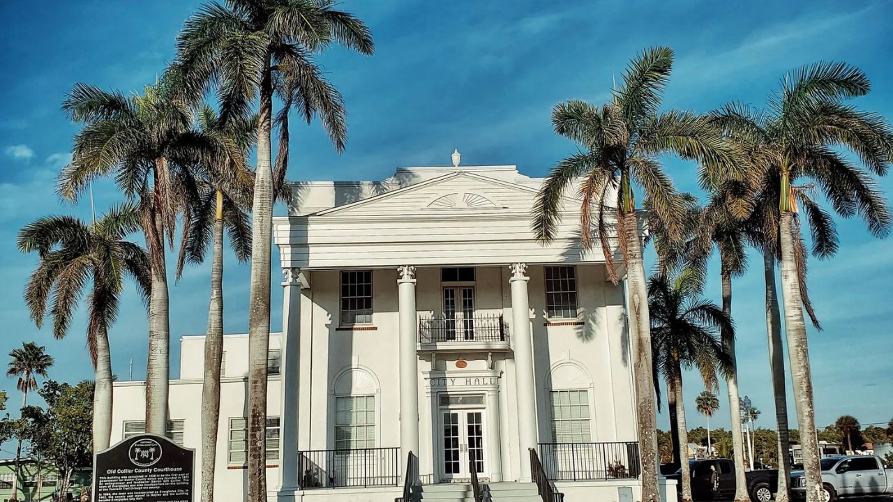 Neoclassical Everglades Museum building with columns and palm trees.