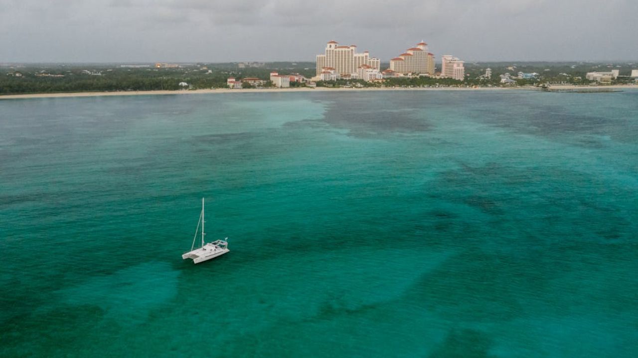 Bahamas Catamaran floating near resort skyline and turquoise sea.